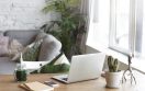 Workplace of modern freelancer leading healthy lifestyle: open generic laptop computer, cactus in pot, smart phone, copybook and glass of green smoothie on wooden desk in stylish home office interior